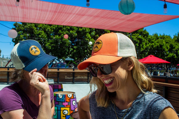 Two women wearing Smog City recycled trucker hats