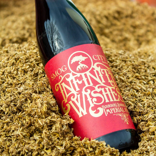 Bottle of Infinite Wishes laying in a pile of malt grain used in brewing