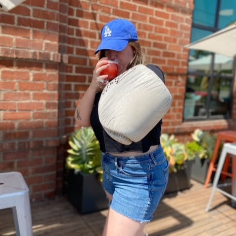 Woman wearing boxing glove and drinking a beer wearing an LA Dodgers hat standing on a patio in front of a brick wall